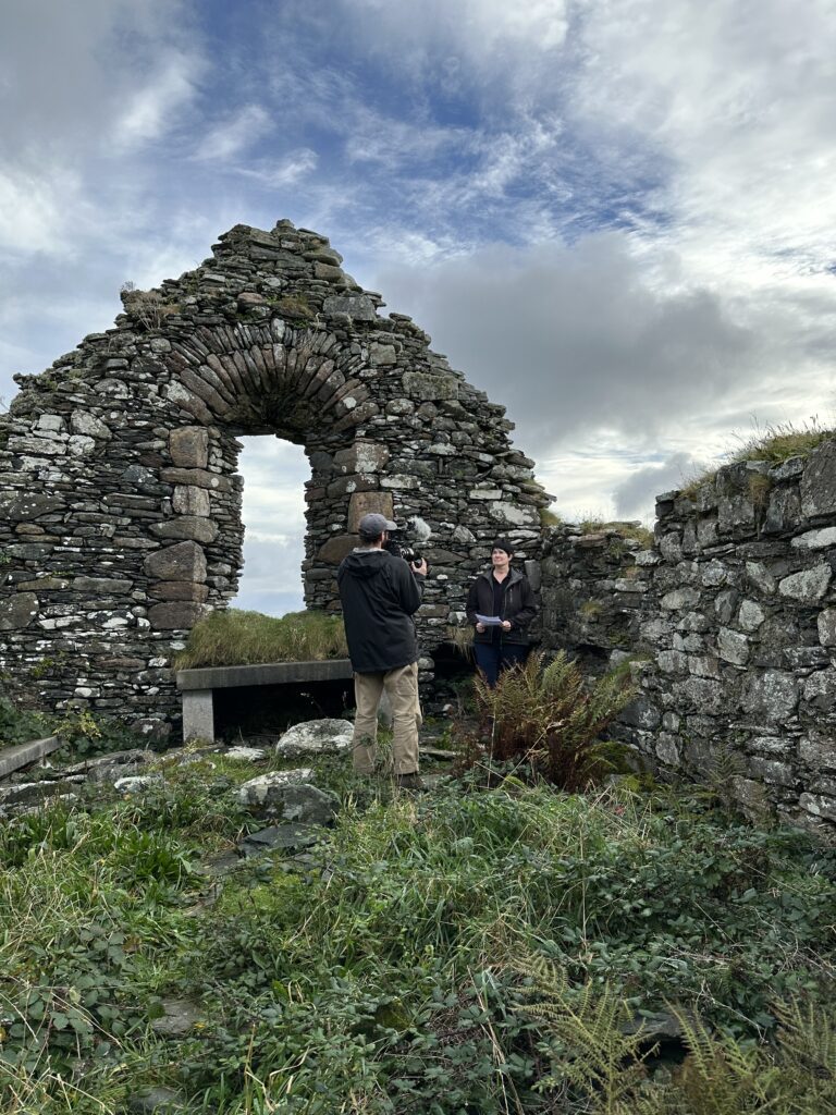 Filming of a person talking to camera inside the ruins of an Irish abbey